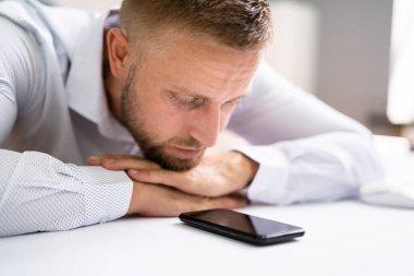 Ofis masasında telefon bekleyen adam.