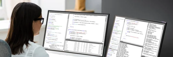プログラマーの女性デスクでコンピュータ上のコーディングソフトウェア — ストック写真