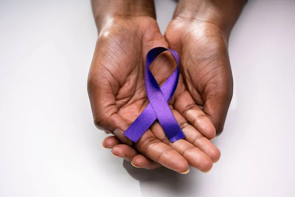 Human Hand Showing Violet Ribbon To Support Pancreatic Cancer Awareness