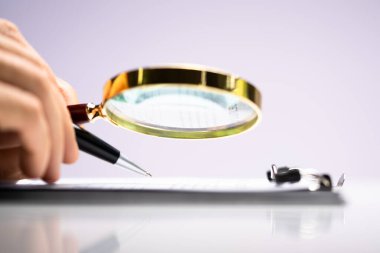 Avukat, büyüteçle inceleme yapıyor. İş Vergisi Dolandırıcılığı Soruşturması