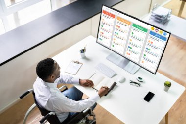 Bilgisayarda Kanban yazılımı kullanarak tekerlekli sandalyedeki engelli Afrikalı Amerikalı Adam