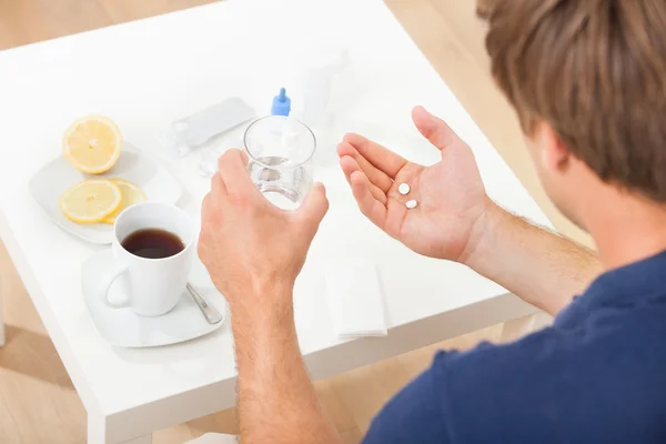 Hombre sosteniendo píldoras y agua — Foto de Stock