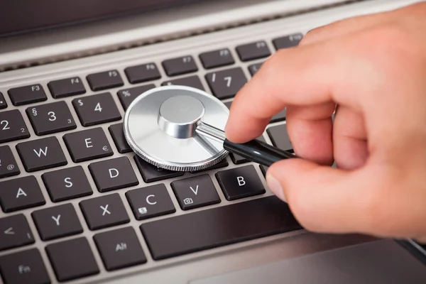 Hand undersöka laptop med stetoskop — Stockfoto