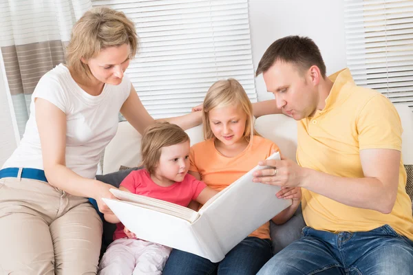 Familie schaut sich Fotos in Fotobuch an — Stockfoto