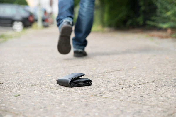 Man walking wobec upadłego portfel na ulicy — Zdjęcie stockowe