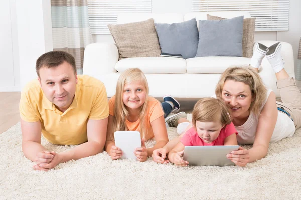 Kinderen met behulp van tabletten liggen op tapijt — Stockfoto