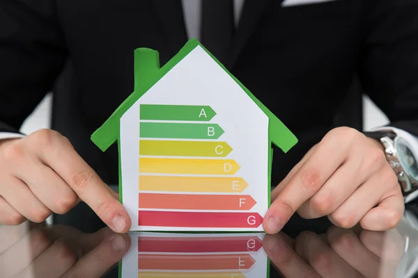 Geschäftsmann zeigt Energieeffizienzdiagramm am Hausmodell — Stockfoto