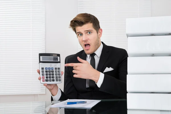 Потрясенный бизнесмен смотрит на калькулятор — стоковое фото