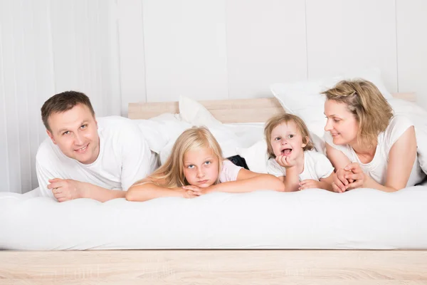 Familia joven acostada en la cama — Foto de Stock