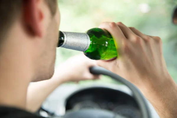 Hombre beber alcohol mientras conduce coche — Foto de Stock