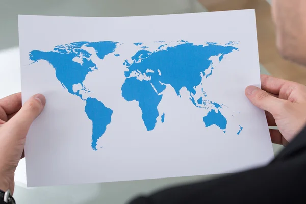 Empresario sosteniendo mapa del mundo — Foto de Stock