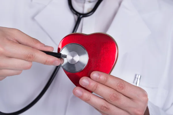 Доктор с помощью стетоскопа исследует форму сердца — стоковое фото