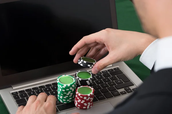 商人与堆积的扑克筹码使用便携式计算机 — 图库照片