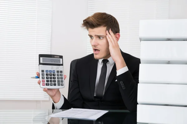 Потрясенный бизнесмен смотрит на калькулятор — стоковое фото
