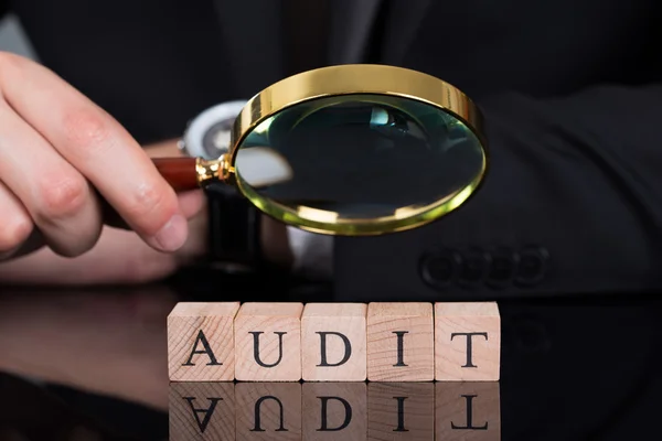 Businessman Examining Audit Blocks Through Magnifying Glass — Stock Photo, Image