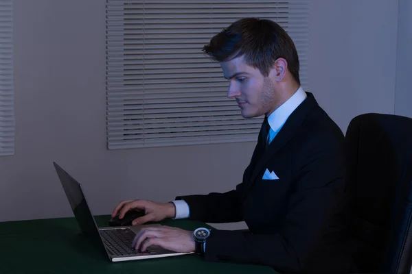 Empresario trabajando hasta tarde en la computadora portátil en el escritorio — Foto de Stock