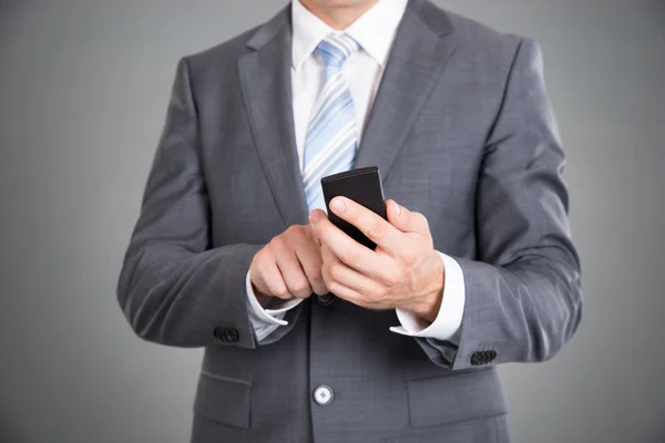 Homme d'affaires tenant un téléphone mobile — Photo