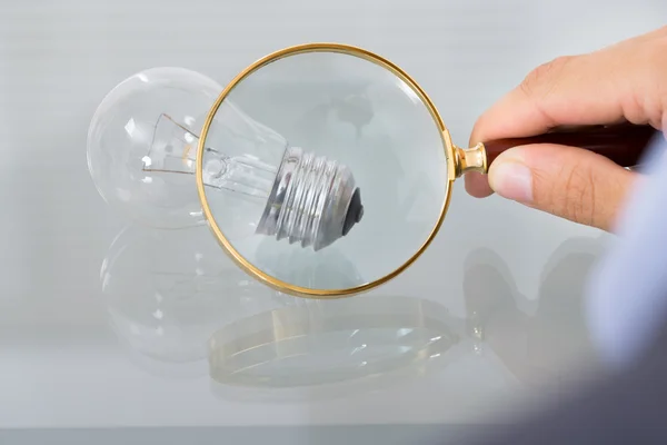 Businessman inspecting lightbulb — Stock Photo, Image