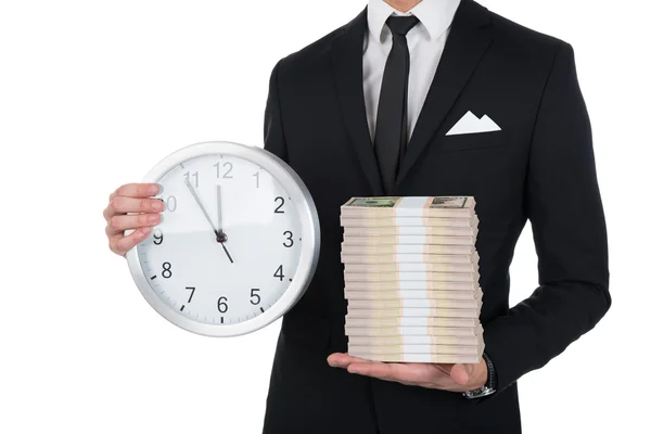 Homme d'affaires tenant horloge et des notes de papier empilées — Photo