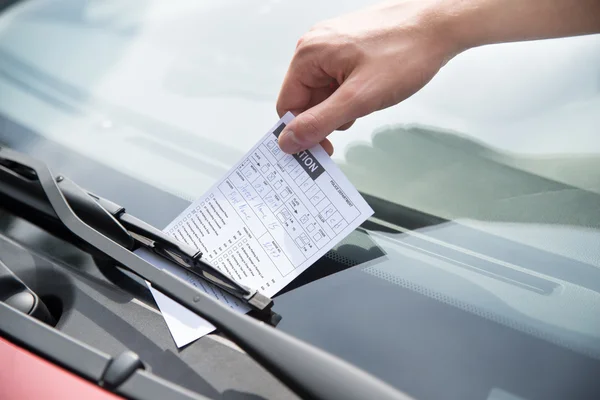 Main de l'officier de mettre un ticket de stationnement sur la voiture — Photo