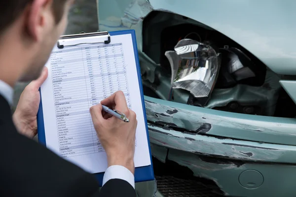 Försäkringsagent granska bil efter olycka — Stockfoto