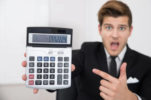 Empresário chocado olhando para a calculadora — Fotografia de Stock