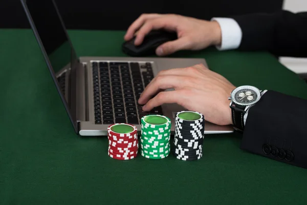 Empresário usando laptop por fichas de poker empilhadas — Fotografia de Stock