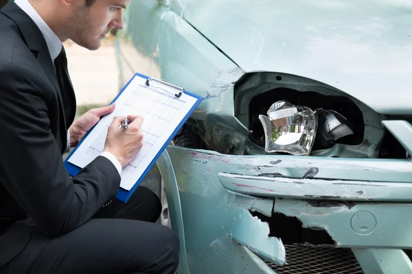 Agente de seguros examinando carro após acidente — Fotografia de Stock