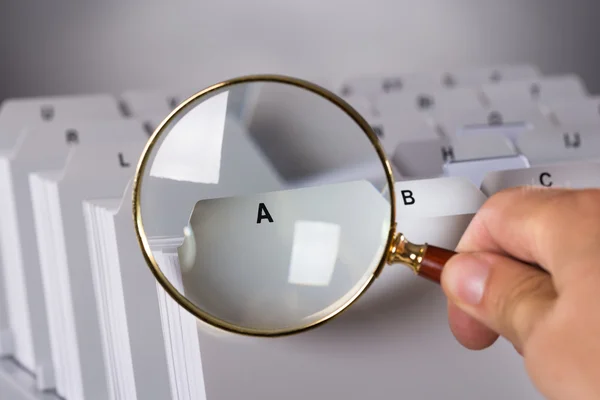 Investigating documents with magnifying glass — Stock Photo, Image