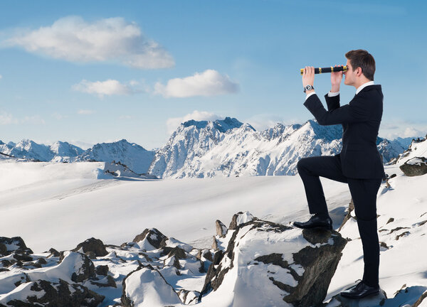 Businessman Looking Through Handheld Telescope In Snow