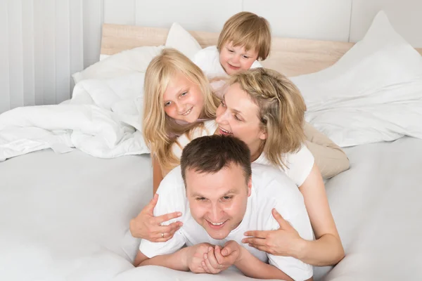 Jovem família deitada juntas na cama — Fotografia de Stock