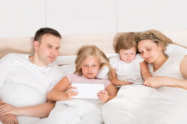 Familia joven usando computadoras portátiles en la cama —  Fotos de Stock