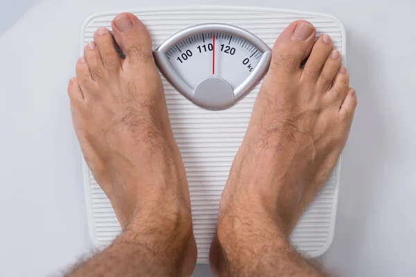 Hombre de pie en la escala de peso — Foto de Stock
