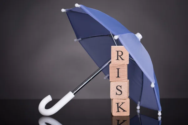 Drewniane klocki ryzyka pod parasolem — Zdjęcie stockowe