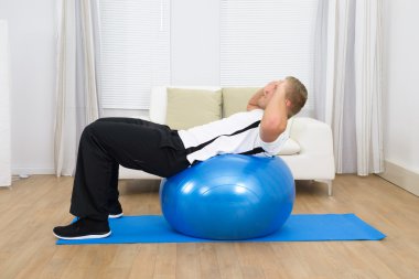Pilates topu eğilerek adam