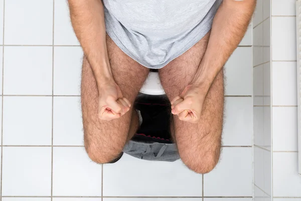 Homme assis sur le bol des toilettes — Photo