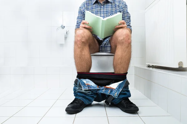 Mann in Toilette liest Buch — Stockfoto