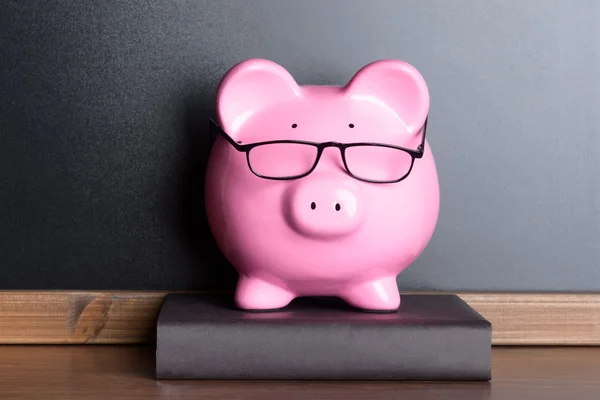 Piggy Bank met een bril op boek — Stockfoto