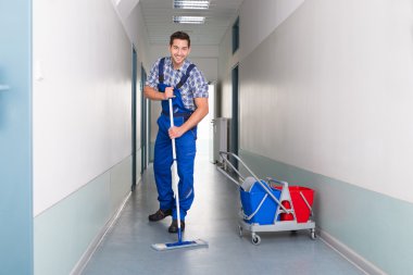 Male Worker Cleaning Office Corridor clipart