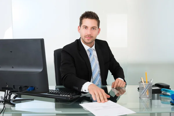 Empresario seguro con documento en el escritorio — Foto de Stock