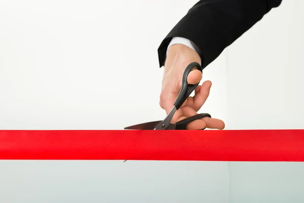 Geschäftsmann schneidet rotes Band mit Schere durch — Stockfoto
