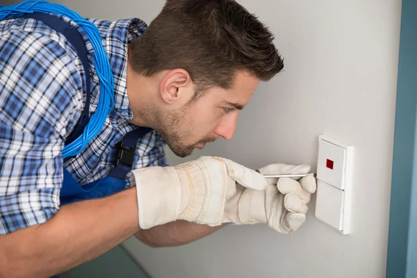 Mann repariert Lichtschalter zu Hause — Stockfoto