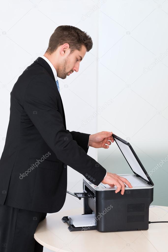 Businessman Using Photocopy Machine In Office