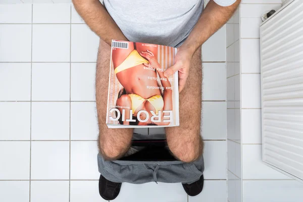Άνθρωπος στην τουαλέτα κατέχουν σέξι περιοδικό — Φωτογραφία Αρχείου
