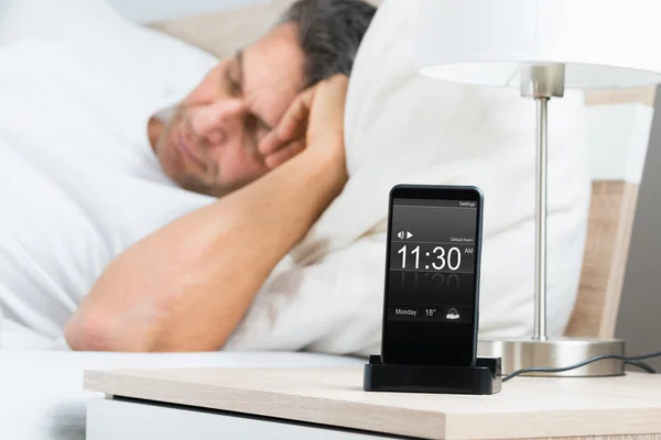 Homme au lit avec alarme sur téléphone portable — Photo