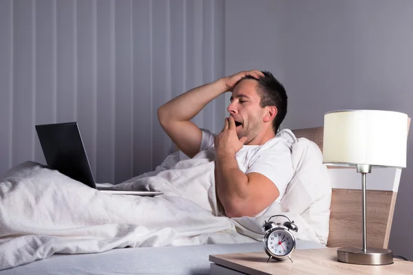 Hombre con el ordenador portátil en la cama — Foto de Stock