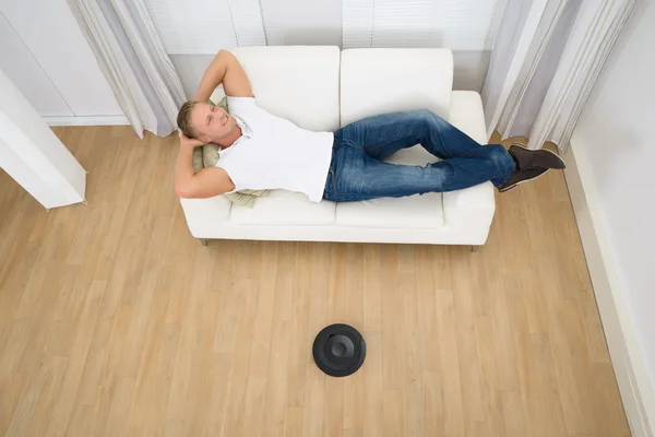 Relaxed Man With Robotic Vacuum Cleaner — Stock Photo, Image