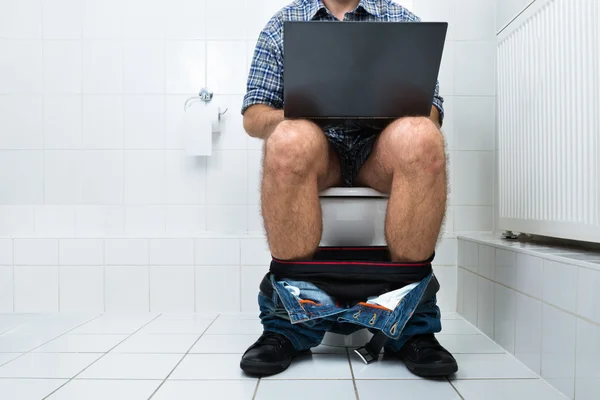 Άνθρωπος στην τουαλέτα, χρησιμοποιώντας φορητό υπολογιστή — Φωτογραφία Αρχείου