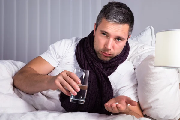 Hombre enfermo sosteniendo píldoras — Foto de Stock