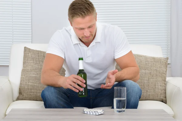 Homme avec bouteille et pilules à la main — Photo